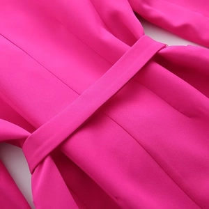 Detail of a magenta blazer featuring a matching waist belt and high-quality woven fabric