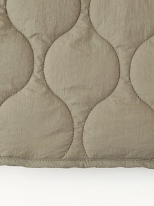 Détail du matelassage en vagues et des coutures sur le tissu de la veste verte olive