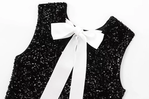 Close-up of sparkling black sequins and large white bow detail on party dress