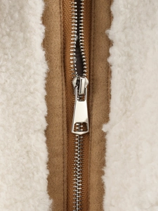 Detailed close-up of premium metal zipper on beige fleece and brown contrast panel
