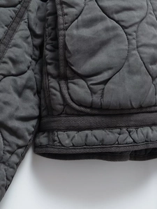 Détail macro d'une veste matelassée gris foncé avec bordure en ruban renforcé