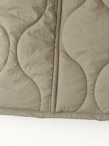 Macro du tissu matelassé vert olive avec surpiqûres en oignon et ourlet précis