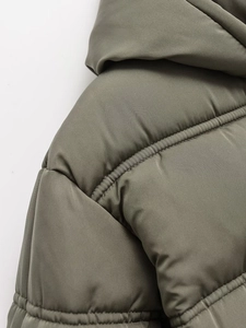 Detailed macro view of olive green quilted shoulder and stitching on padded jacket