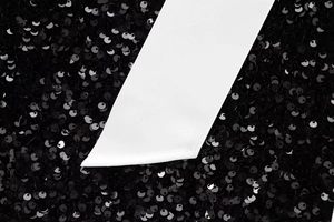 Detail of shimmering black sequins paired with a textured white ribbed ribbon tie