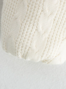 Detailed macro view of ivory white chunky cable knit texture on a cozy winter cardigan