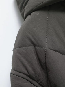 Detail view of deep olive quilted jacket showing shoulder stitching and fabric texture