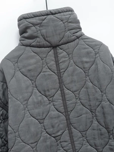 Gros plan sur une veste matelassée grise avec coutures ondulées et col montant épais