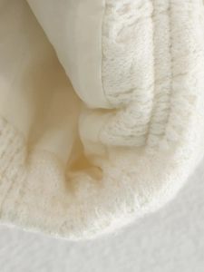 Close-up of cream knit jacket showing thick wool texture and smooth inner lining