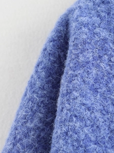 Dettaglio ravvicinato della trama in maglia blu del cardigan con fiocco minimalista