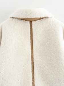 Back view of cream faux shearling jacket featuring brown suede seam and fuzzy texture