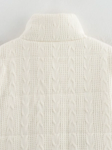 Detail shot of the cream cable knit texture and stand-up collar on the thick winter coat
