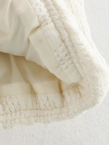 Dettaglio del tessuto a maglia bianco testurizzato e fodera in raso della giacca