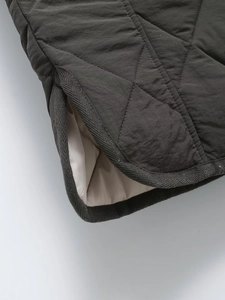 Detailed close-up of grey quilted diamond pattern fabric with beige lining and knit edges