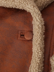 Gros plan sur le daim marron avec doublure en peau lainée beige et bouton assorti