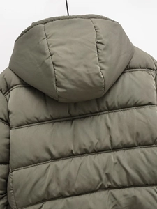 Detail of the hooded olive green quilted jacket showing stitching and fabric texture