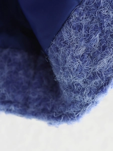 Dettaglio del tessuto in lana blu a contrasto con morbida fodera in pile su un cardigan