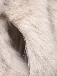 Close-up detail of soft faux fur texture in cream and light brown with long plush fibers