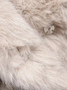 Detail of soft beige faux fur texture with a round silver snap button on the lapel