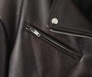 Détails des boutons pression du col et de la poche zippée d'une veste en similicuir grainé
