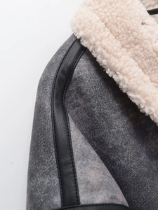 Detailed close-up of faux suede jacket with leather trim and white faux fur collar