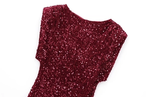 Close-up of sparkling burgundy sequin fabric with round metallic discs on mini dress
