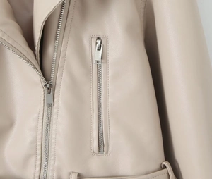 Détail de la veste en similicuir beige avec fermetures éclair argentées et coutures