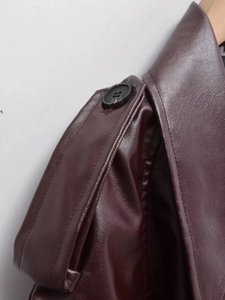 Détail de la veste en similicuir bordeaux foncé avec épaulettes et bouton noir