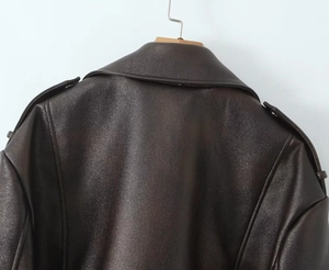 Gros plan sur la texture du cuir et les pattes d'épaule d'une veste de moto marron