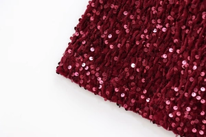 Close-up of burgundy sequined velvet fabric with vertical pleats and luxury texture