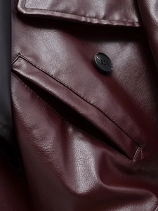Gros plan sur le blouson en cuir PU bordeaux montrant le grain de litchi et les coutures
