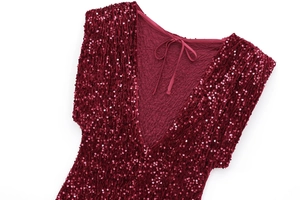 Detail of burgundy sequin mini dress featuring a deep V-neck and sparkling textures
