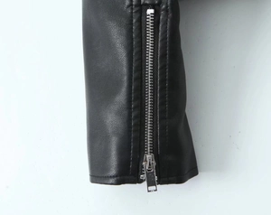 Detail of black faux leather jacket cuff featuring vertical silver metal zipper and pebble grain
