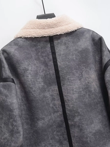 Detail view of grey faux suede biker jacket with white shearling collar and back leather trim