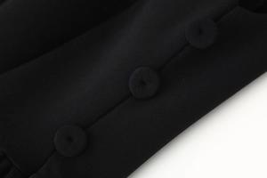 Makro-Detailaufnahme von stoffbezogenen Knöpfen an einem schwarzen, ärmellosen Minikleid
