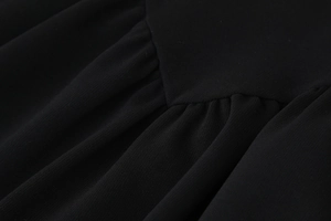 Detailansicht der eleganten Raffung und Textur des schwarzen ärmellosen Minikleids