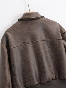 Detail view of the back of a vintage brown PU leather bomber jacket with ribbed hem