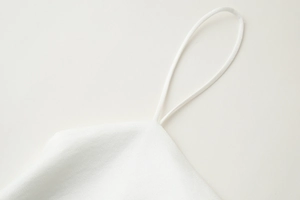 Détail des fines bretelles spaghetti sur un haut en satin de soie blanc luxueux