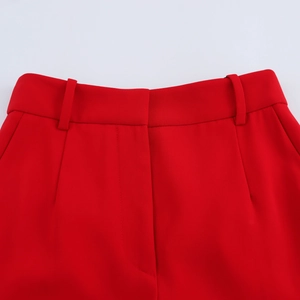 Detail of red high-waisted trousers featuring belt loops and side pockets