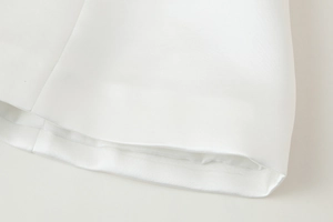 Close-up of white Y2K off-shoulder top showing smooth satin hemline and fine stitching details
