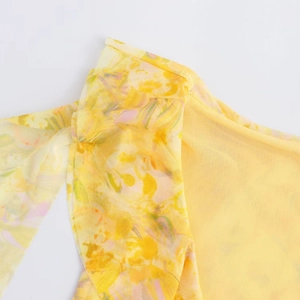Detail of yellow mesh mini dress featuring abstract floral print and ruffled texture