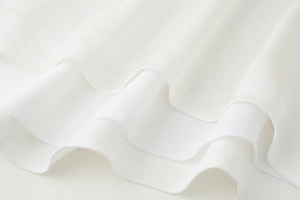 Détail d'un caraco en satin blanc avec ourlet ondulé et coutures surjetées précises