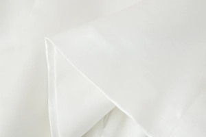 Close-up of white Y2K off-shoulder top showing pleated design and high-quality fabric texture