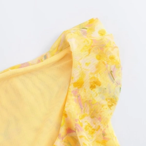 Detail shot of yellow mesh fabric featuring delicate floral prints and layered ruffles