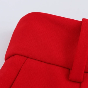 Detailed close-up of red high-waisted trousers featuring wide waistband and belt loops