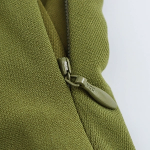 Close-up of olive green dress fabric showing a high-quality YCC metal zipper detail
