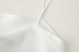 Détail du caraco en satin blanc montrant les fines bretelles et la texture des coutures