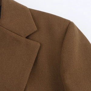 Close-up of brown blazer notched lapel and shoulder with textured twill fabric detail