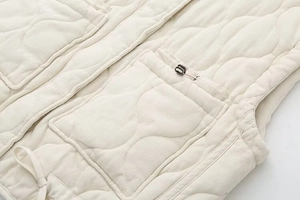 Close-up of wave-quilted vest showing patch pockets and adjustable drawstring hem detail