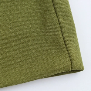 Close-up detail of the grass green knit fabric texture and high-quality stitching on dress