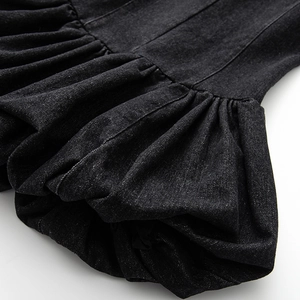 Macro shot of pleated black denim fabric texture and seam details on a sleeveless dress